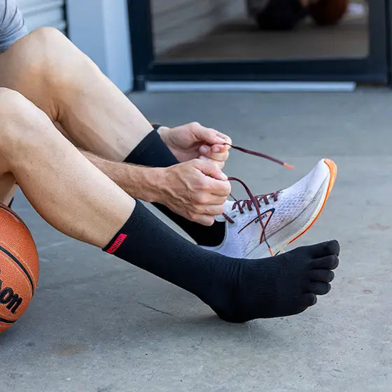 Svart tåstrumpa från Injinji i knähög modell, med individuella tåfack och ribbad struktur. Perfekt för sport och vardag med fokus på naturlig fotrörelse och komfort