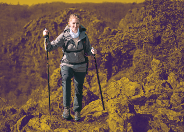 kvinna vandrar med lätthet i wandertoes 2.0 och stavar upp för stenig och tuff terräng. 
